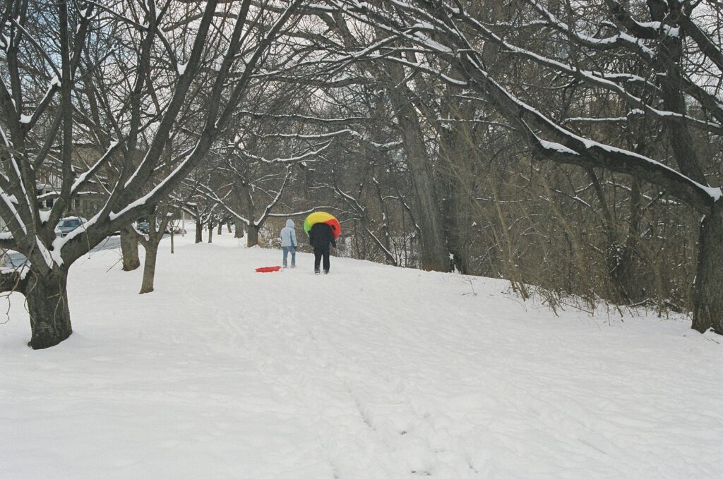 Twp children carrying their sleds in the snow .