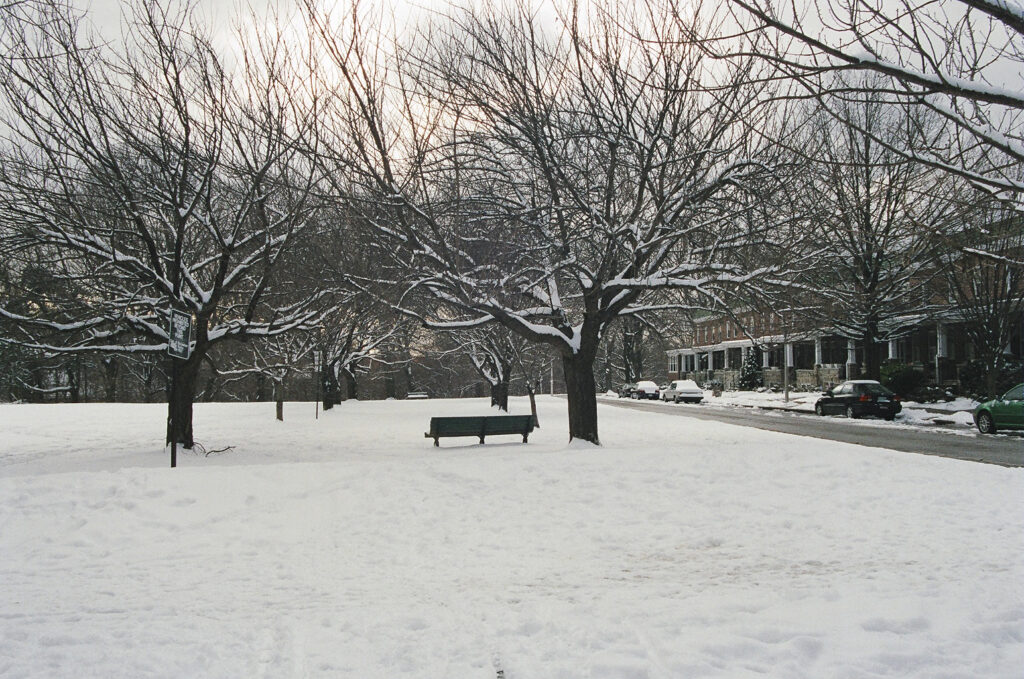 Snow covered park with rowhouses in background.