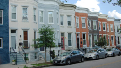 A row of bow-front brickhouses. Some are painted, some have the natural brick.