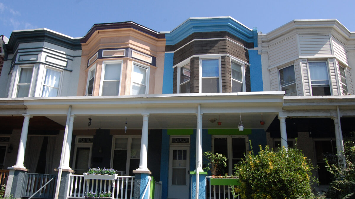 Multi-colored Victorian wooden bow-front row houses with covered porches.