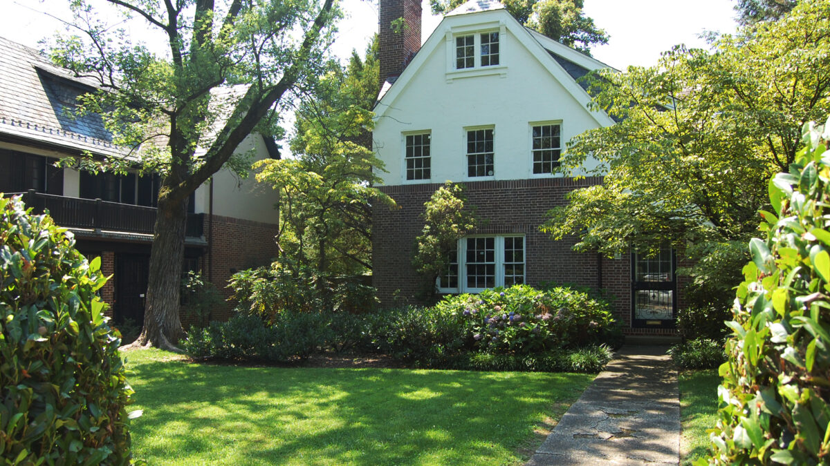 Detached, brick and stucco, tudor style row home with front lawn.