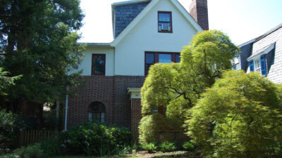 Detached multilevel Tudor Style home with Japanese maples in the front yard.