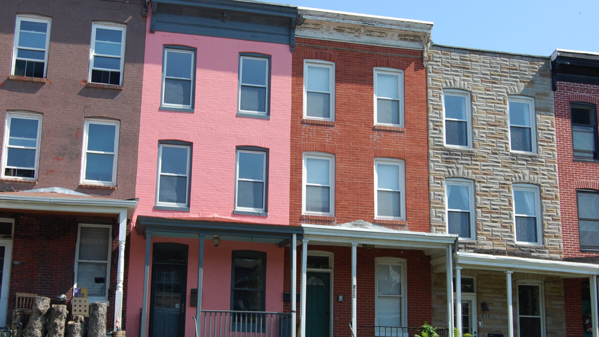 Three story multi-colored brick rowhouses with porches.