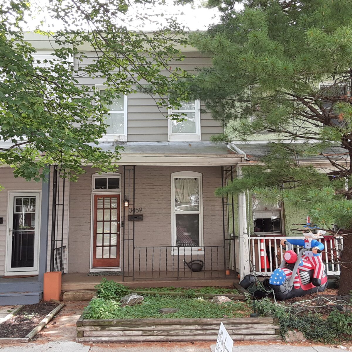 Rowhouse with siding and decorated yards.