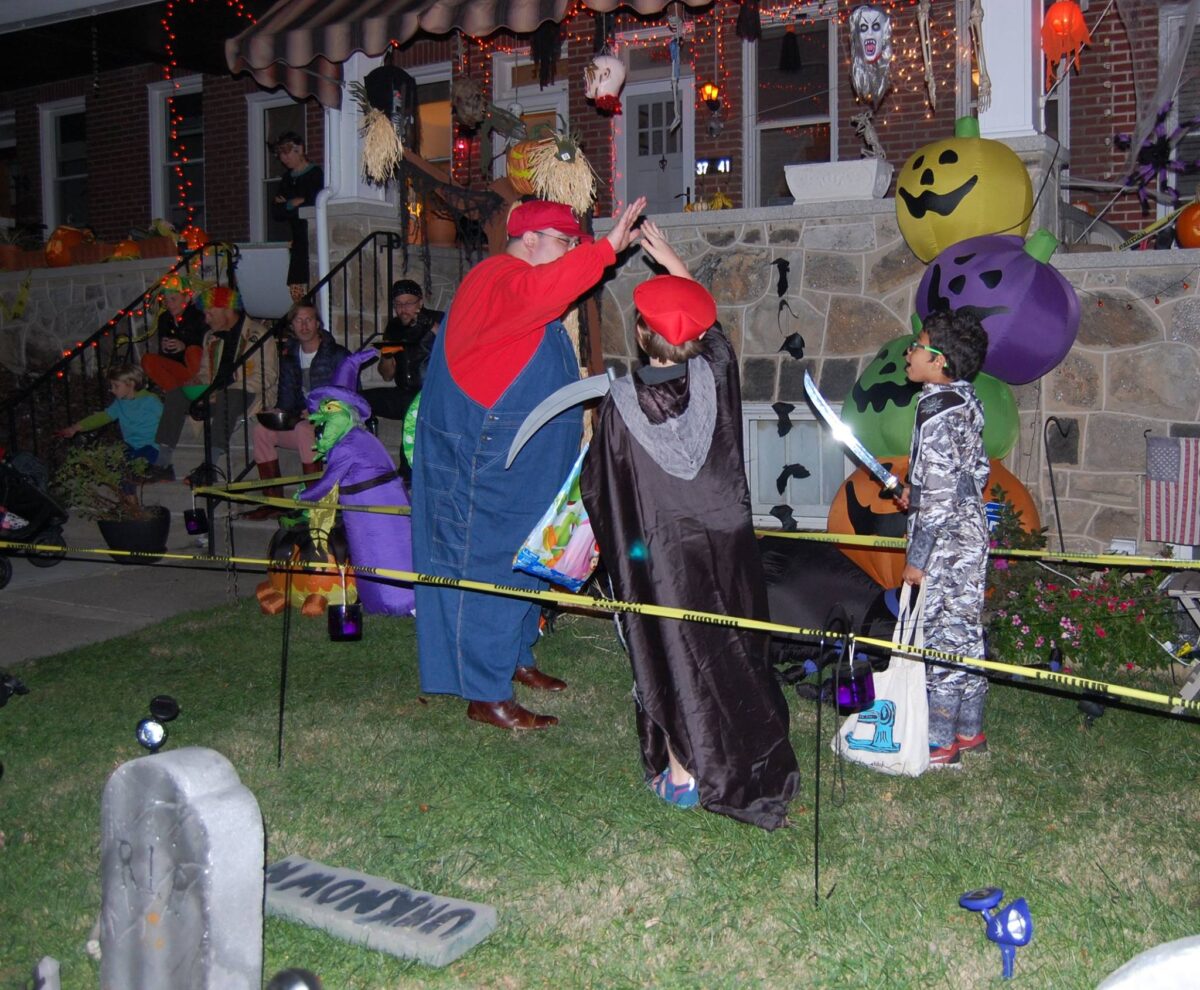 Halloween: many neighbors sitting on their steps waiting for approaching trick or treaters.