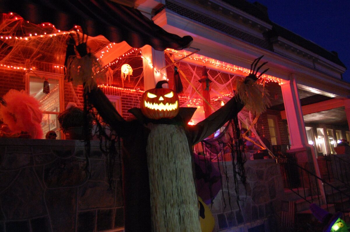 Halloween: yard decorations with a tall figure with a jack o lantern head and stretched out arms