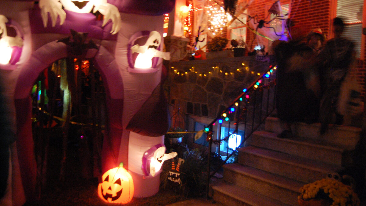 Halloween: A row home with a haunted house display in the front yard and many trick or treaters.