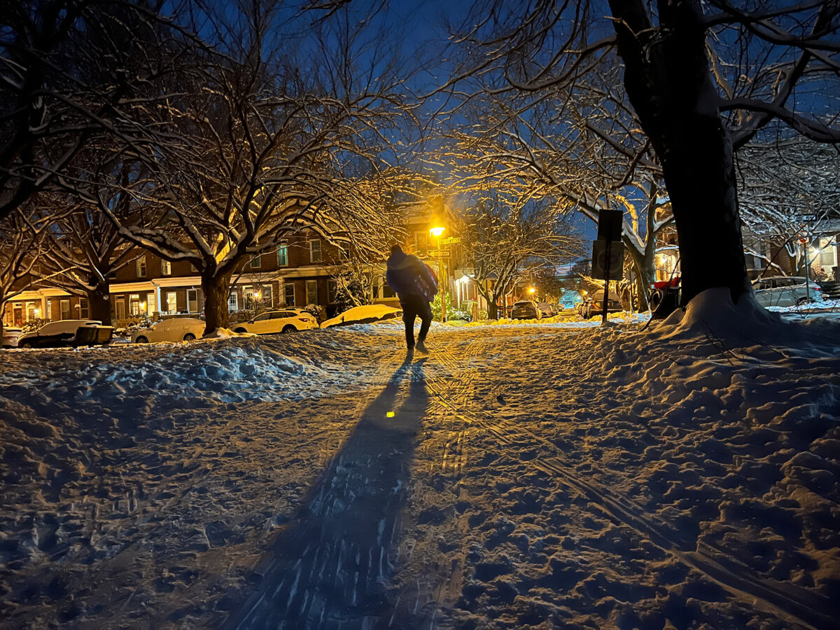 Sledder climbing the hill in the twilight, returning from a day sledding in the park.