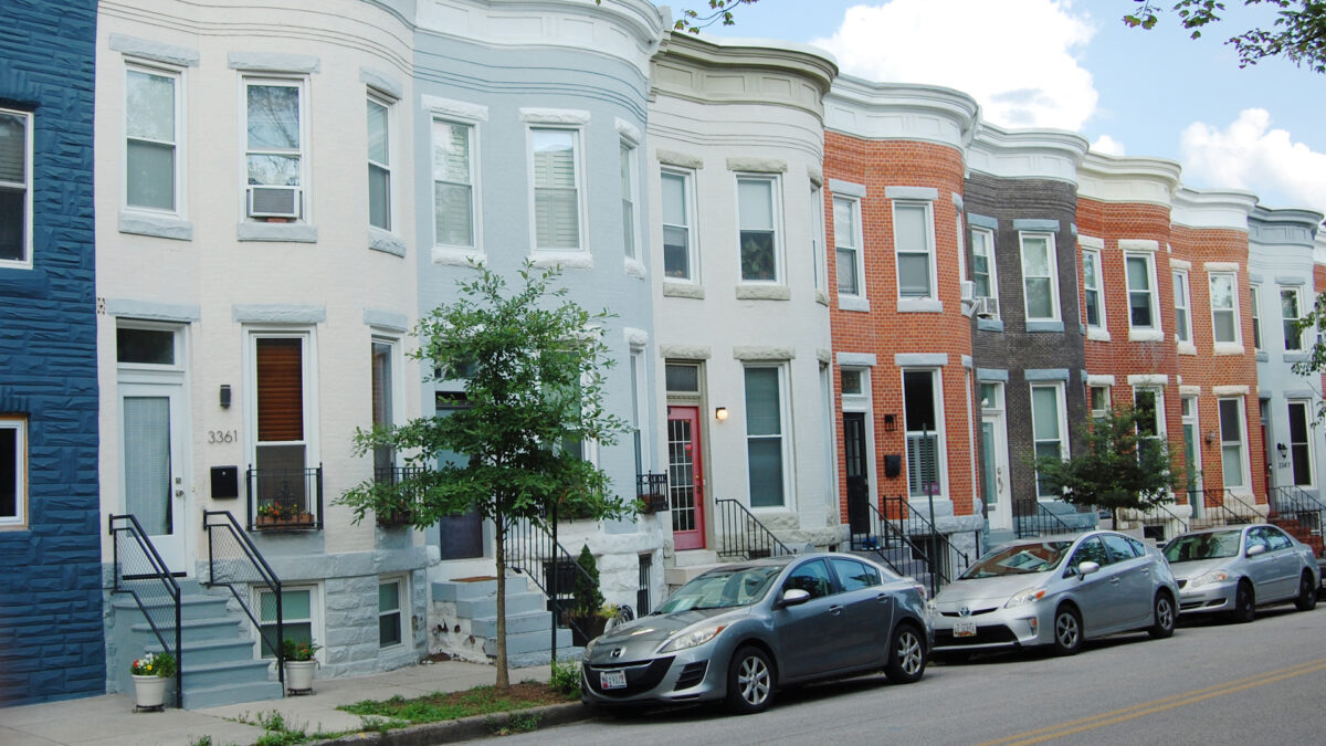 Bowfront brick rows with front steps and glass-paned doors. Some houses are painted pastel colors, some have unpainted brick.