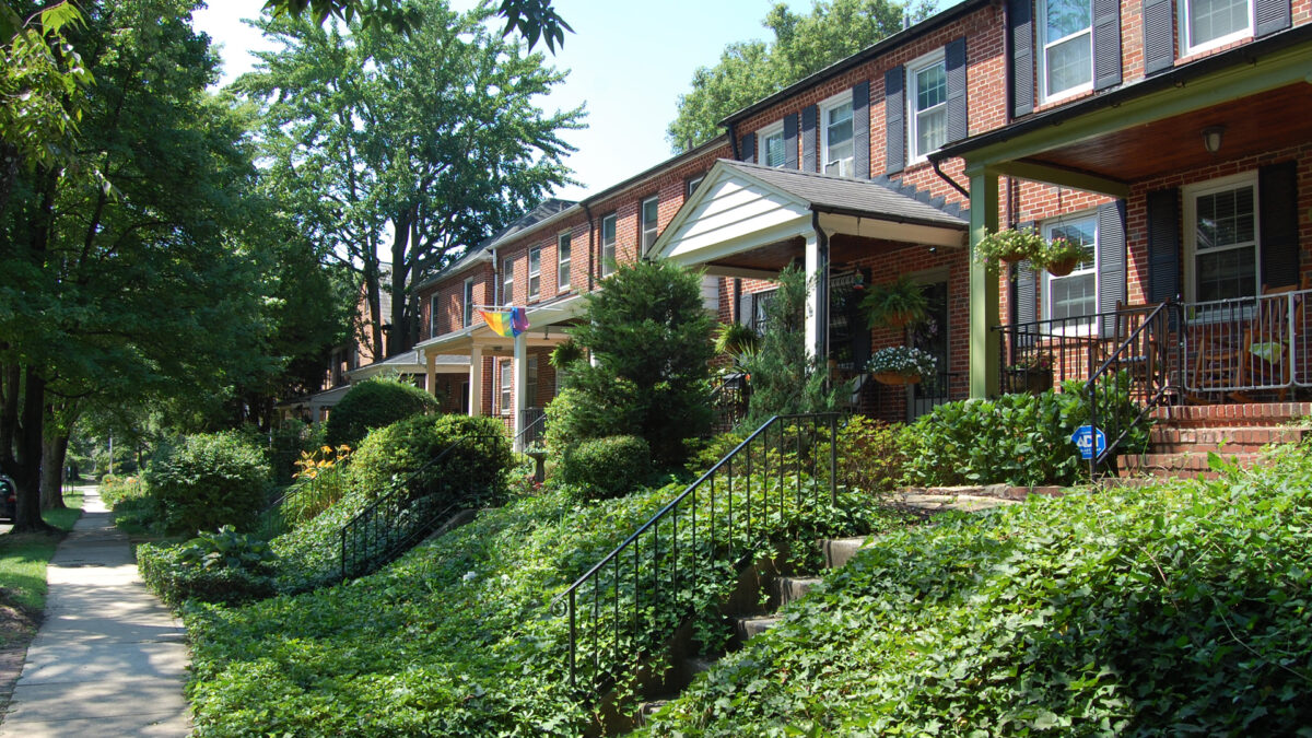 Brick rowhouses with green gardens and shady trees.